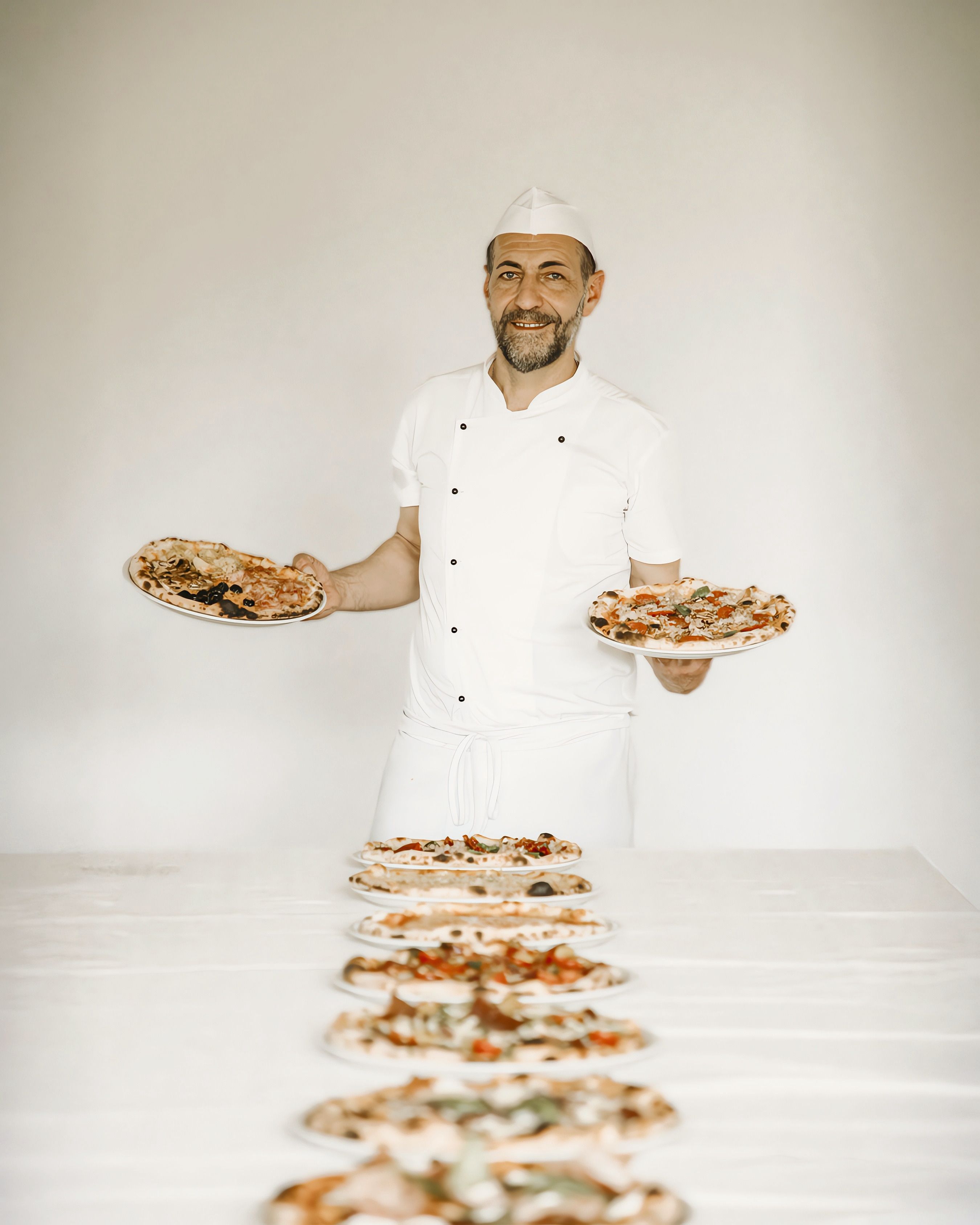 The pizzaiolo with a row of freshly baked pizzas